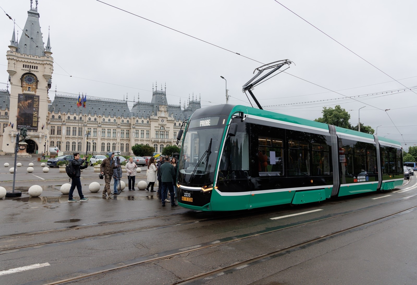 Tramvai verde pe o arteră urbană, în fața unei clădiri istorice